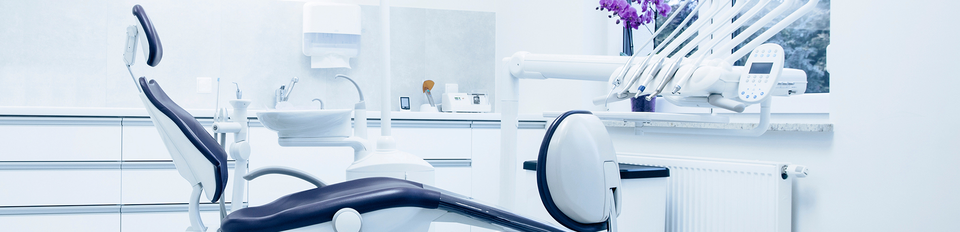 The image shows a modern dental clinic interior with various pieces of equipment, including a dental chair and an X-ray machine.