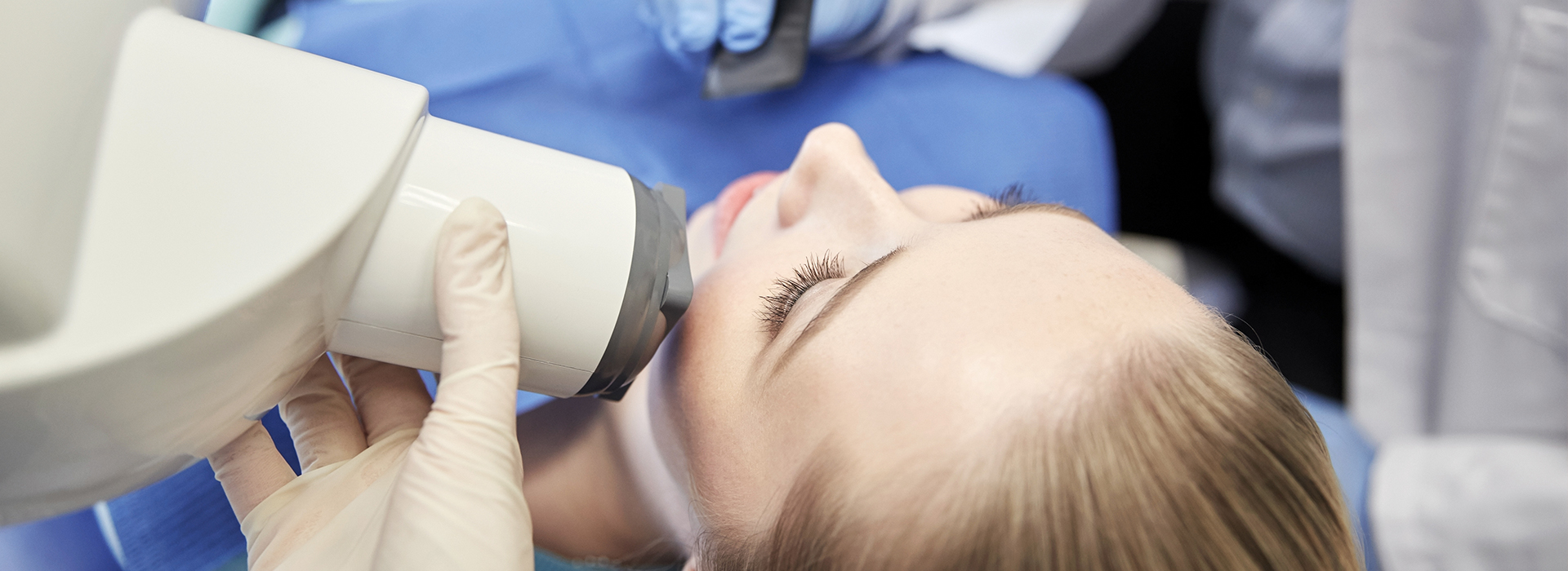 A person receiving a dental examination with a dentist using a magnifying loupe.